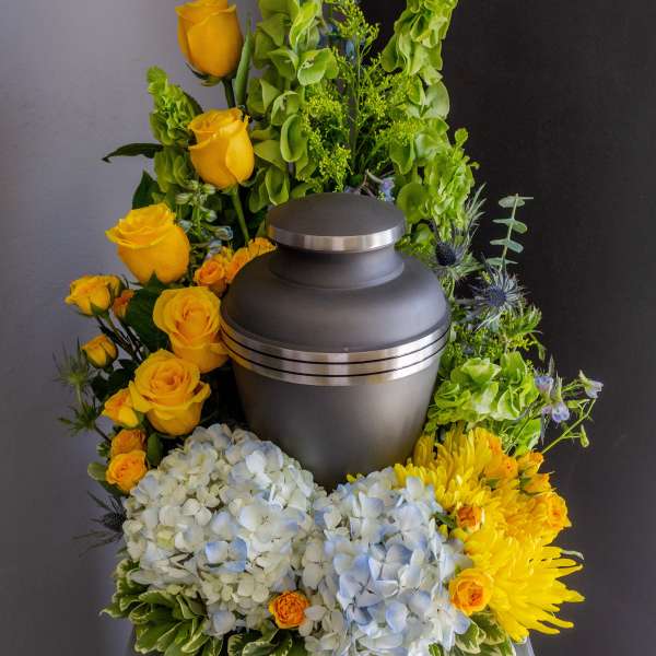 Funeral urn surrounded by yellow roses, hydrangeas, and chrysanthemums