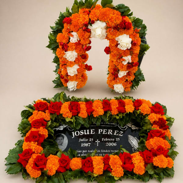 Floral funeral tribute with orange marigolds, red roses, and white roses around a memorial plaque