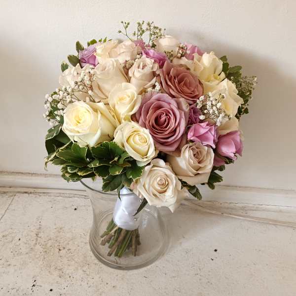 Bouquet of cream, pink, and lavender roses in a clear glass vase