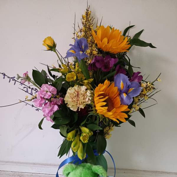 Colorful mixed bouquet with a green teddy bear at the base