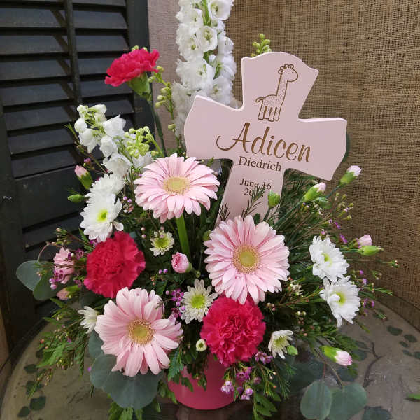 Pink and white floral arrangement with a cross-shaped sign