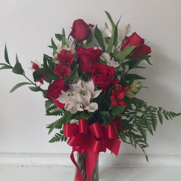 Red roses and white lilies in a glass vase with a red ribbon
