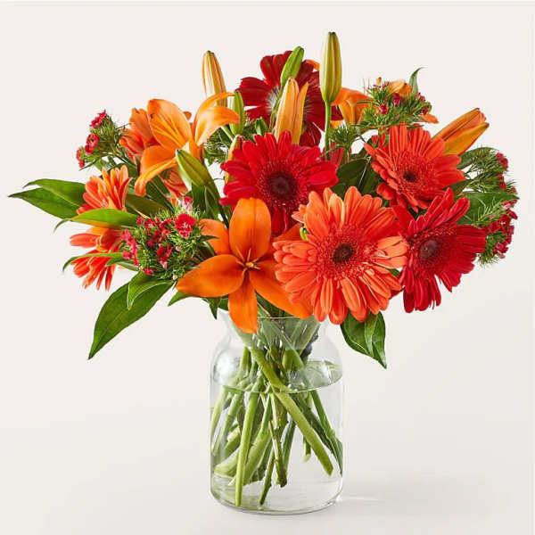 Bouquet of orange and red flowers in a clear glass vase