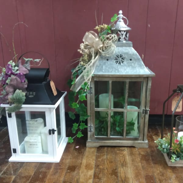 Decorative lanterns with candles and floral accents on a wooden floor