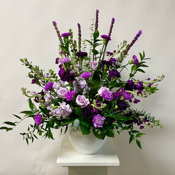 Purple floral arrangement in a white vase