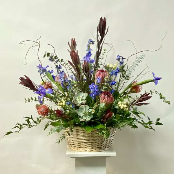 Tall mixed flower arrangement in a wicker basket
