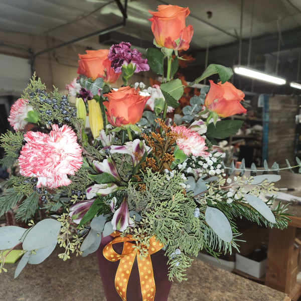 Bouquet of orange roses and pink carnations in a vase
