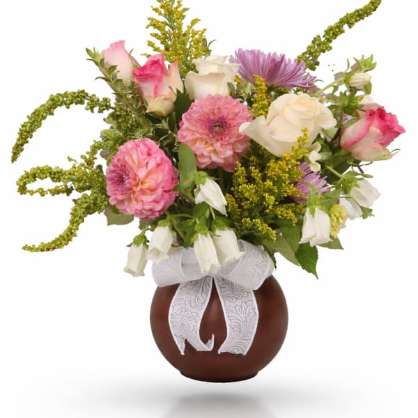 Bouquet of pink and white flowers in a brown vase with a white ribbon