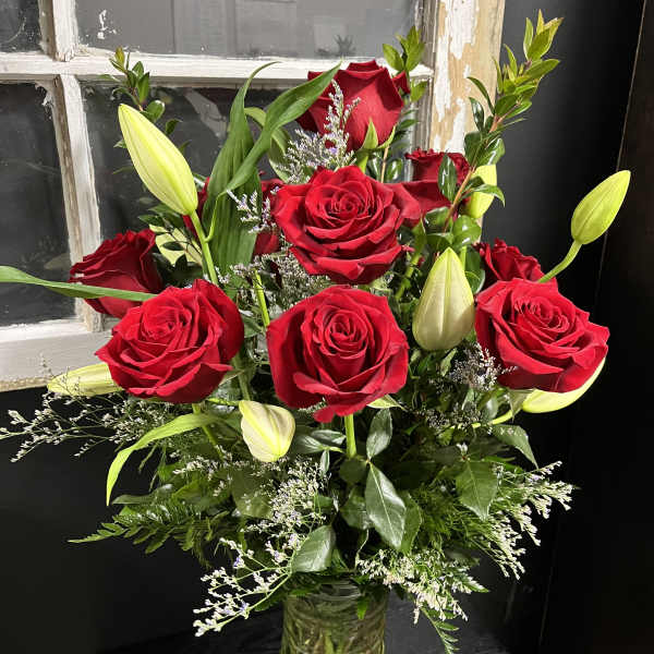 Red roses and lily buds in a clear glass vase