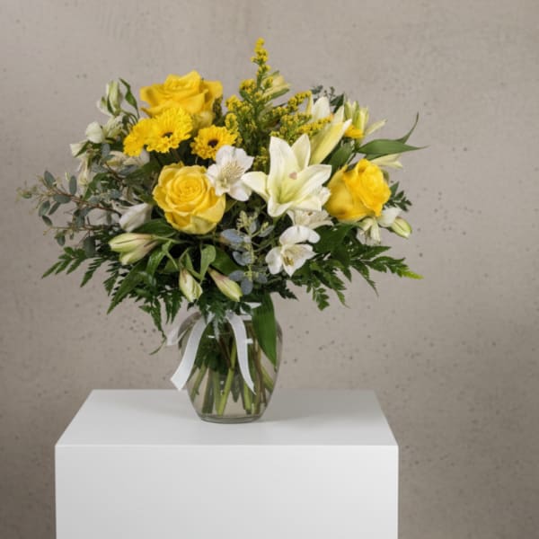 Yellow and white flower bouquet in a clear glass vase