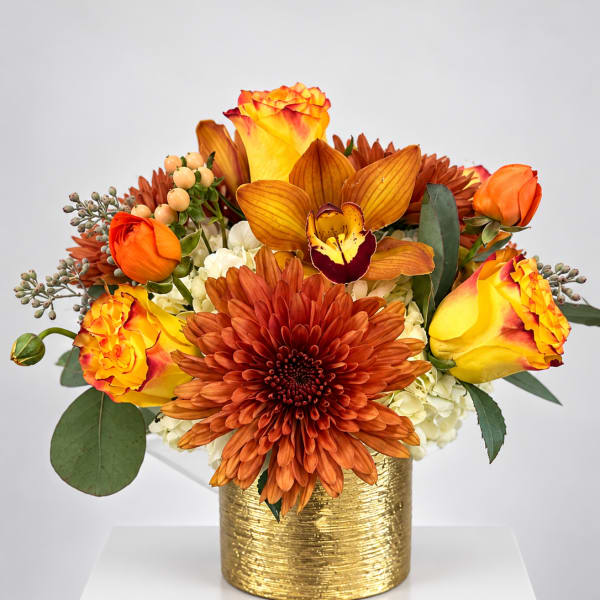 Orange and yellow floral arrangement in a gold vase