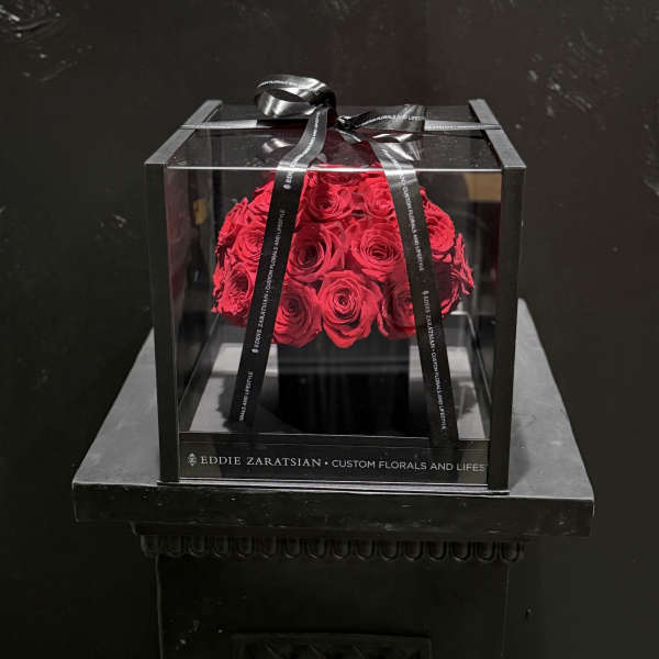 Red roses in a clear square box tied with a black ribbon
