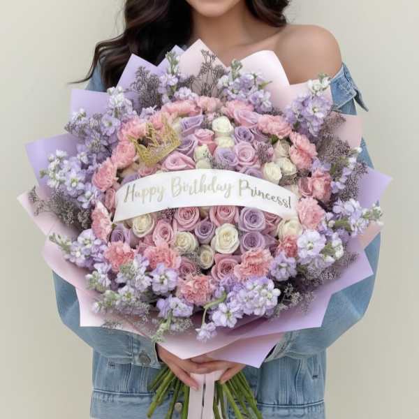 Large pastel bouquet of roses, carnations, and lilac flowers with a birthday ribbon