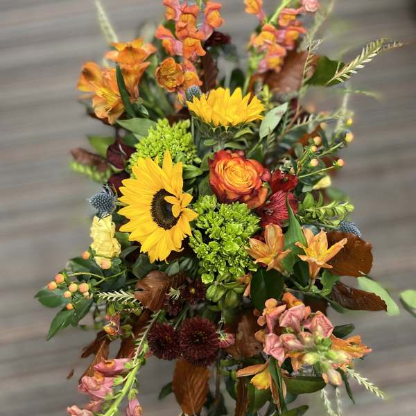 Mixed bouquet with sunflowers, orange blooms, and pink snapdragons