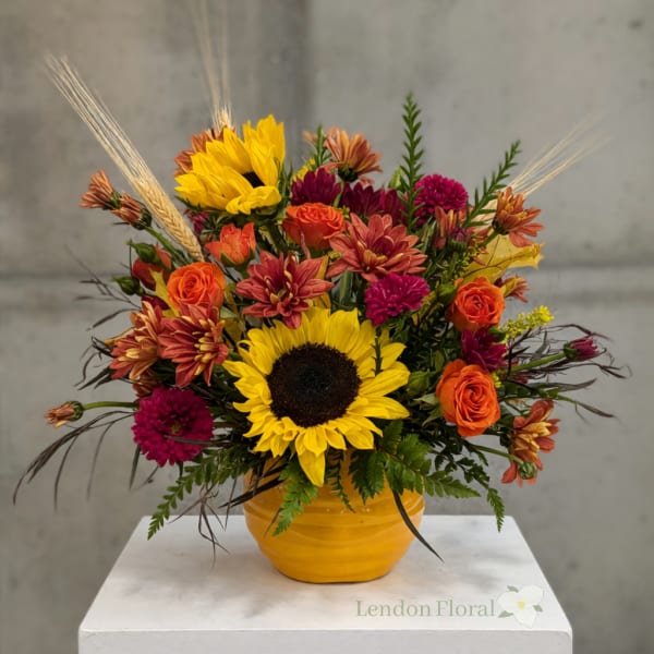 Sunflower and orange flower arrangement in a yellow vase