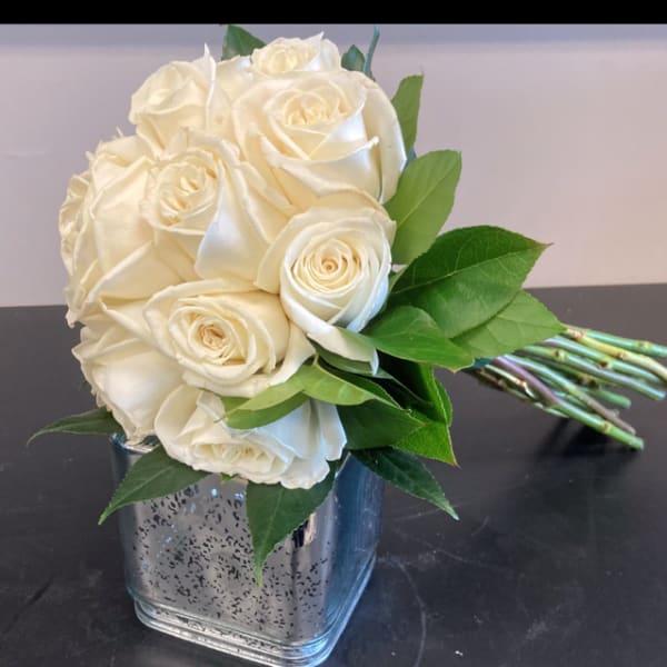 White rose bouquet in a square glass vase with green leaves