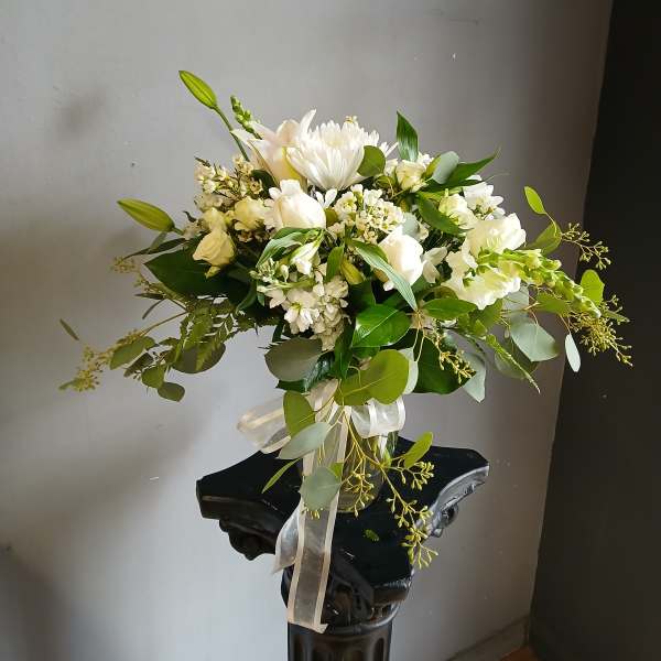 White floral arrangement in a glass vase with a ribbon