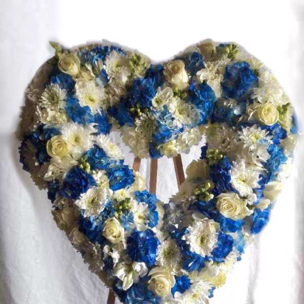 Heart-shaped floral arrangement on an easel with blue and white flowers