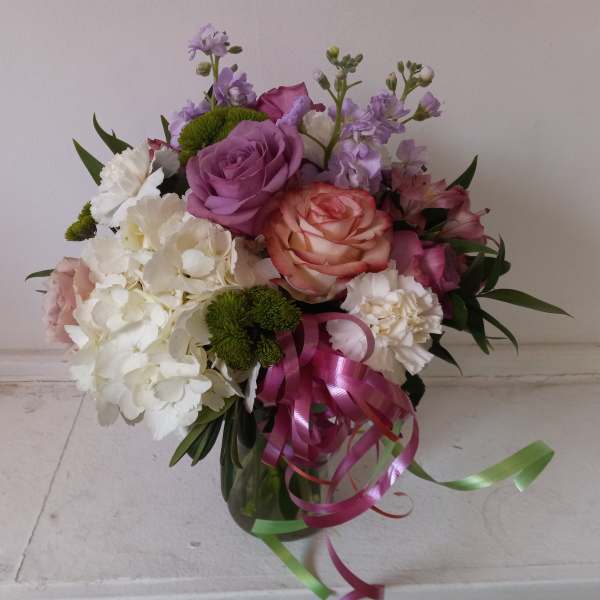 Bouquet of pink, white, and lavender flowers with ribbon in a glass vase