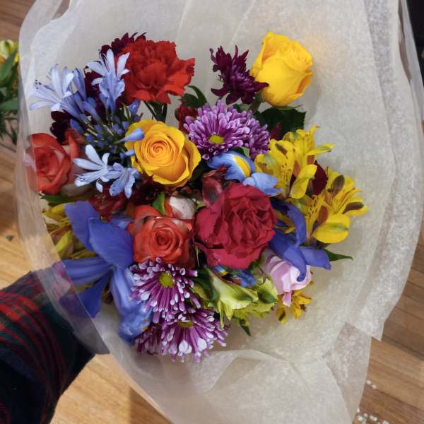 Mixed bouquet of roses, carnations, and daisies wrapped in white paper