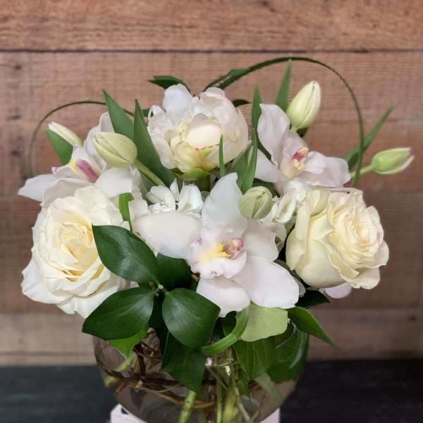 White roses and orchids arranged in a glass vase