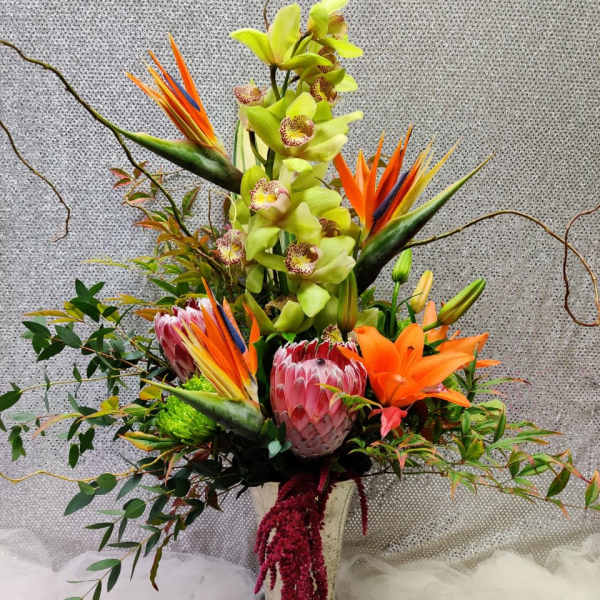 Tall tropical arrangement with orchids, bird of paradise, and lilies in a vase