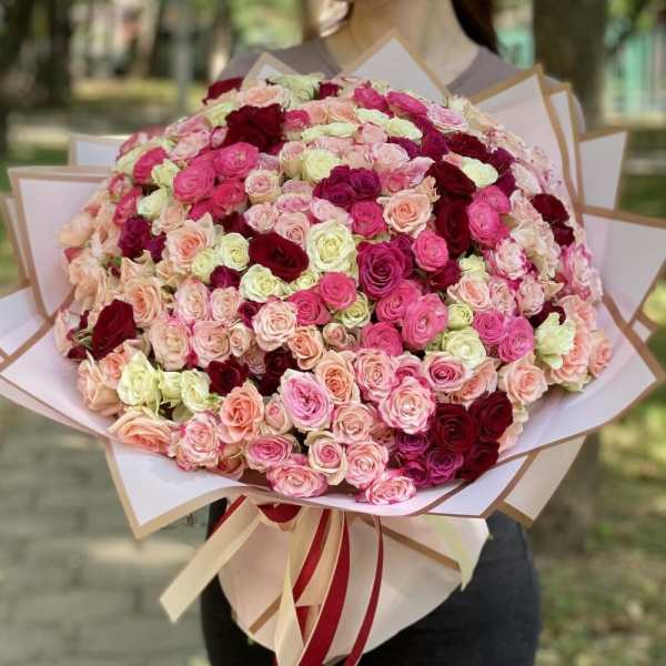 Large bouquet of pink, blush, and burgundy roses wrapped in paper