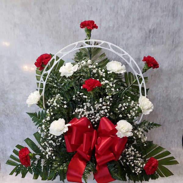 Standing floral wreath with red and white carnations and a red bow
