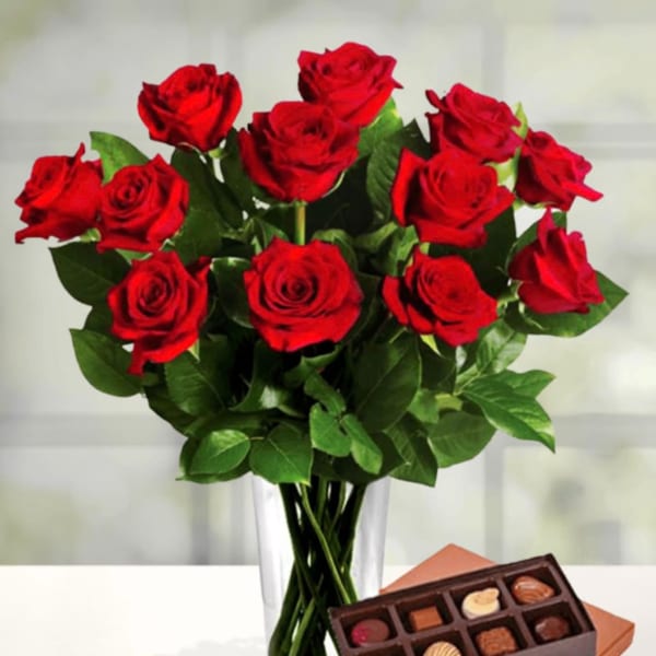 Red roses in a clear vase with a box of chocolates