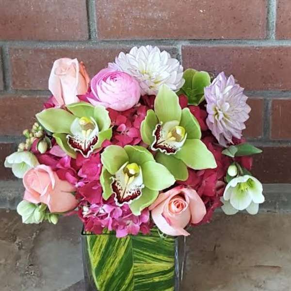 Pink and green floral arrangement in a square glass vase