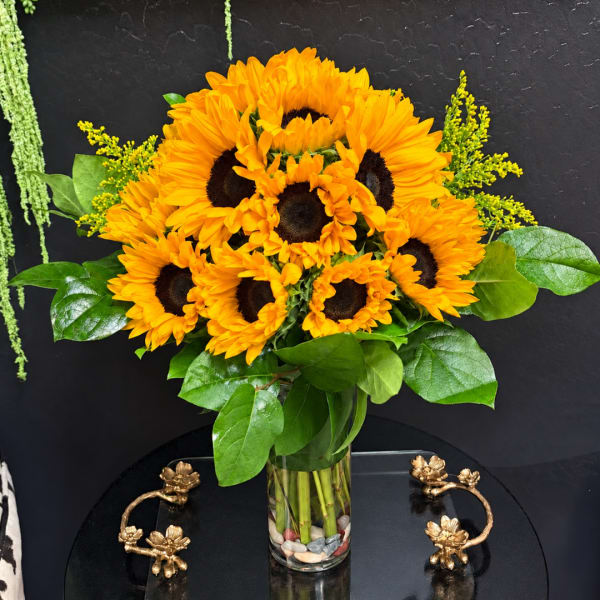 Sunflower bouquet in a clear glass vase with green foliage