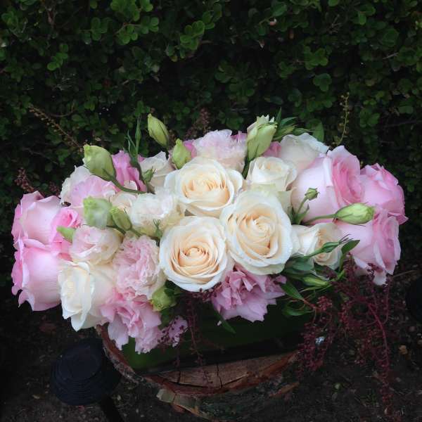 Pink and white rose bouquet with pale blooms in a low container
