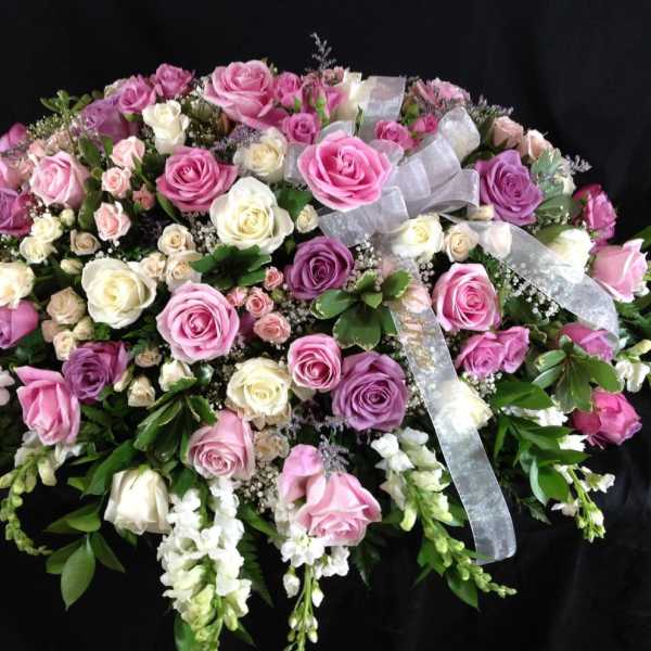 Large arrangement of pink, purple, and white roses with ribbon