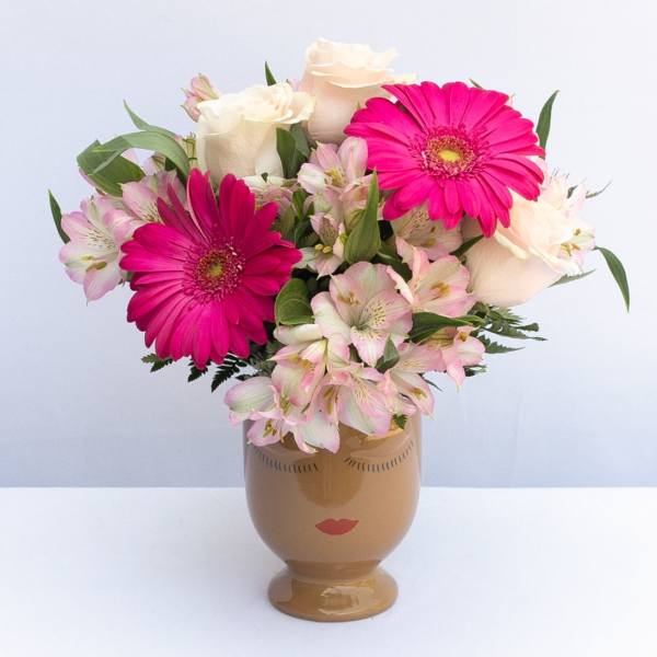 Pink and white flowers arranged in a face-shaped vase