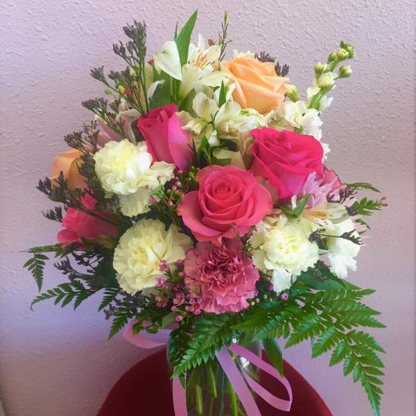 Bouquet of pink and peach roses with white flowers in a glass vase