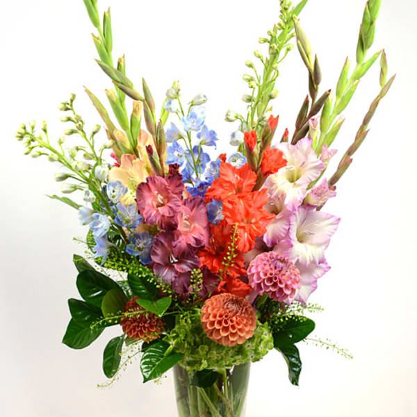Tall mixed bouquet in a glass vase with colorful blooms and long spikes