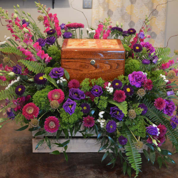 Colorful floral arrangement surrounding a wooden urn box