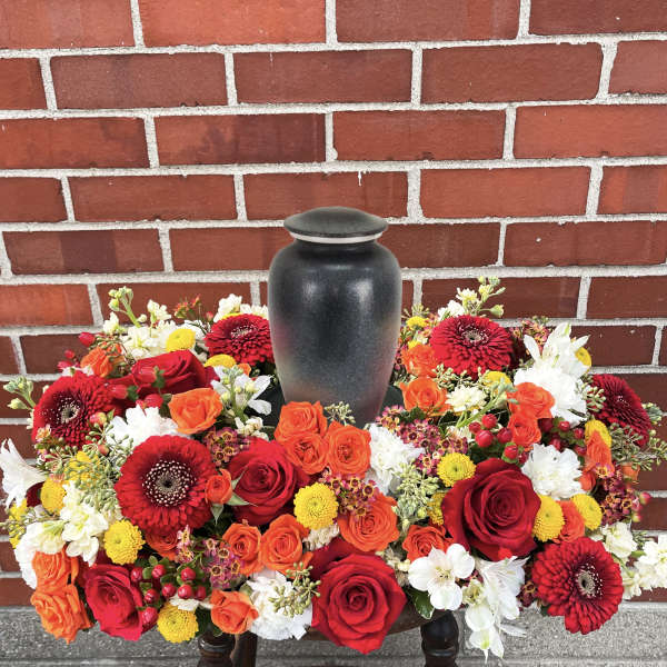 Red, orange, and white floral urn arrangement around a black vase