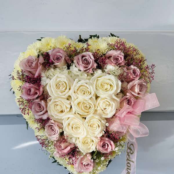 Heart-shaped bouquet of pink and white roses with a pink ribbon