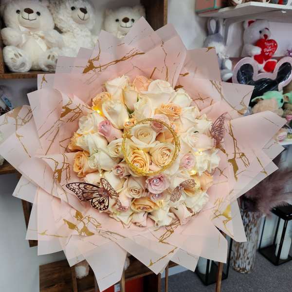 Bouquet of cream and blush roses wrapped in pink paper