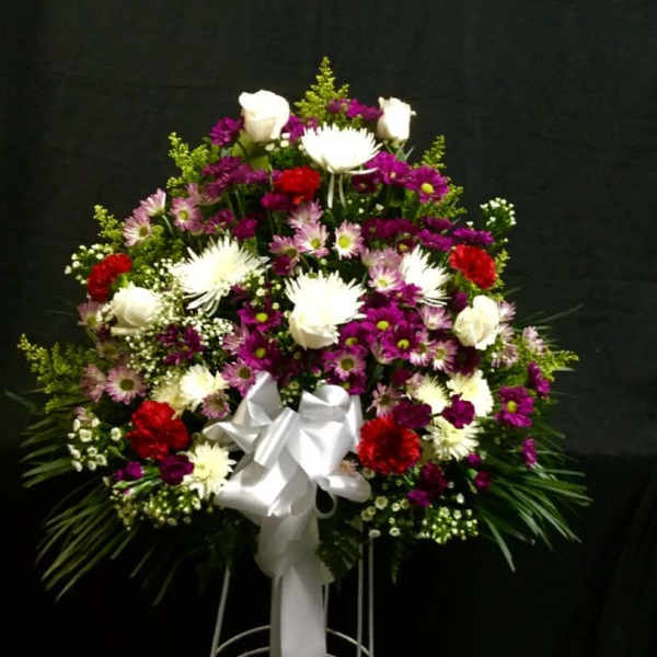 Standing floral spray with white, purple, and red flowers on a white easel