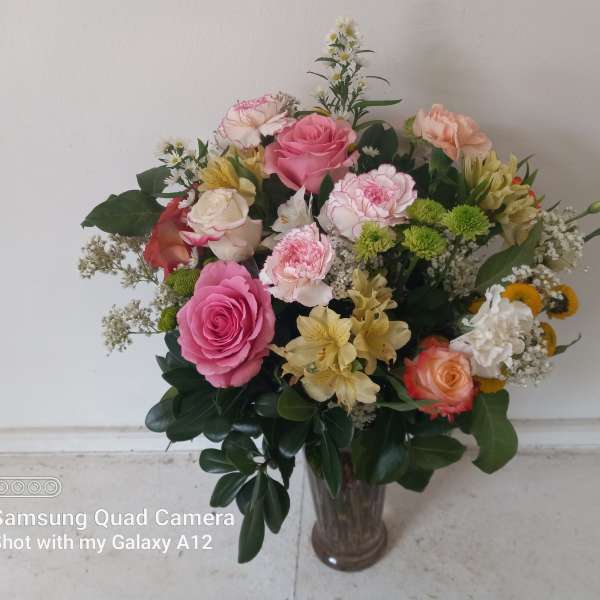 Mixed bouquet of pink, peach, and white flowers in a glass vase