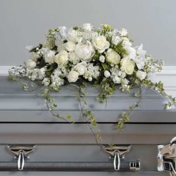 White floral casket spray with trailing greenery