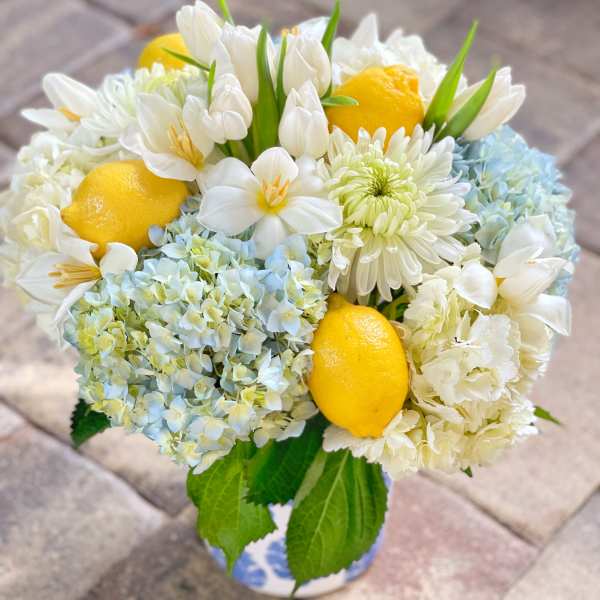 Bouquet of white flowers with lemons and pale blue blooms in a vase