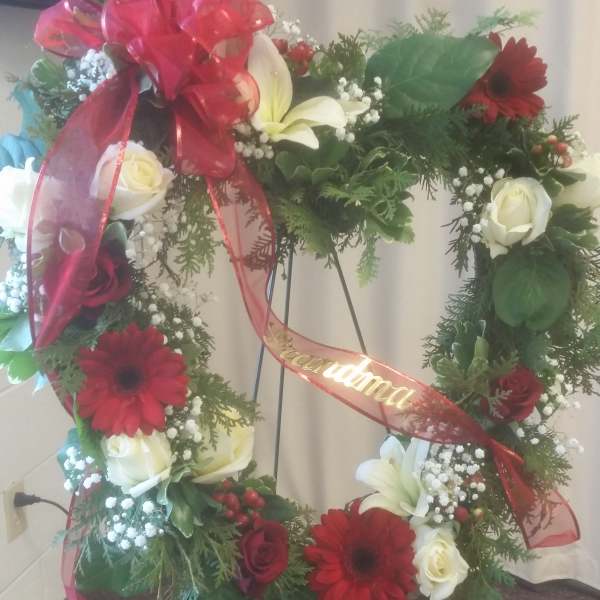 Heart-shaped floral wreath with red and white flowers on a stand