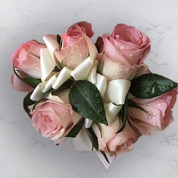Pink rose bouquet with white ribbon on a light surface