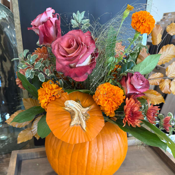 Pink roses and orange marigolds arranged in a pumpkin vase