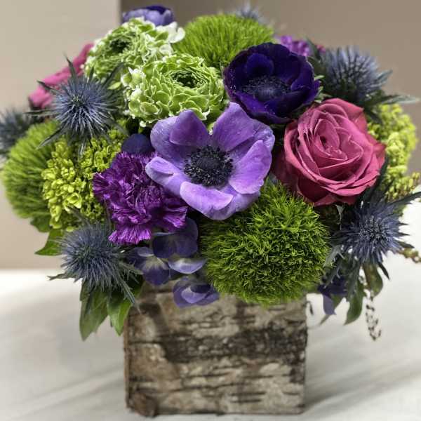 Bouquet of purple, pink, and green flowers in a birch-style box