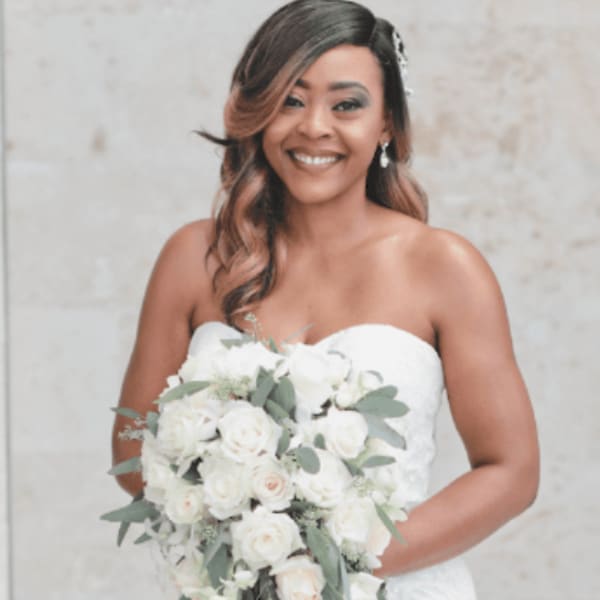Bride holding a cascading bouquet of white roses and greenery