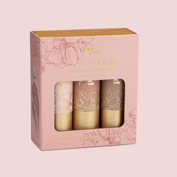Pink boxed set of three jumbo lip tints with floral illustrations and a clear window.